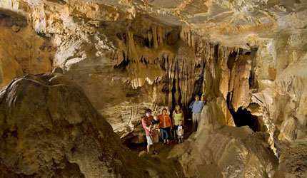 Cave Scene for Mammoth Onyx; Family with small children posing among drapery in the cavern.